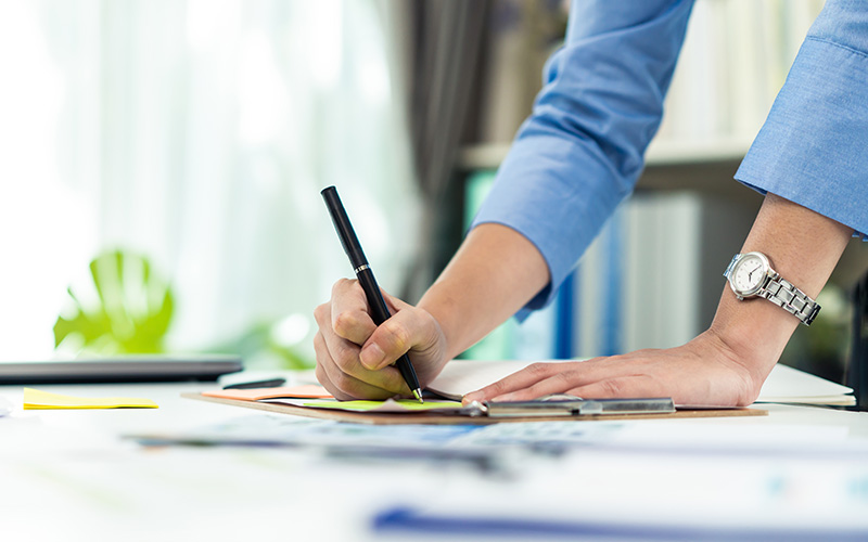 A person engaged in writing on a sheet of paper